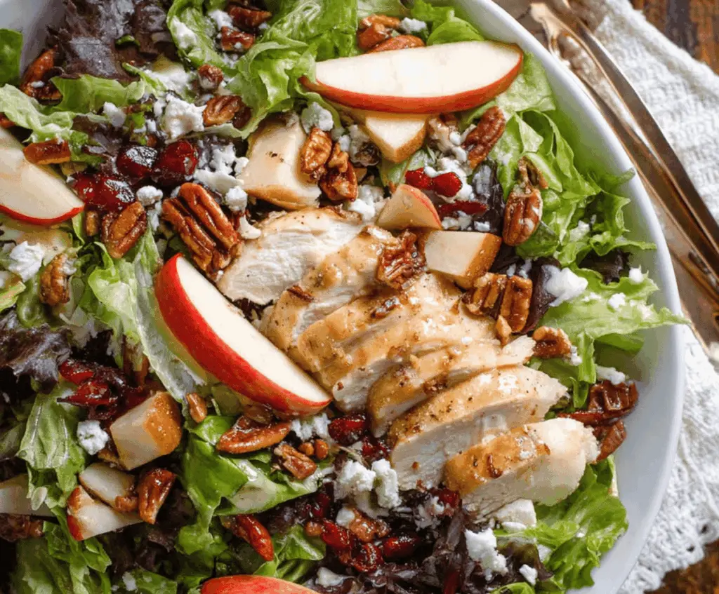 Delicious apple pecan chicken salad with fresh greens, sliced apples, toasted pecans, and grilled chicken in a creamy dressing