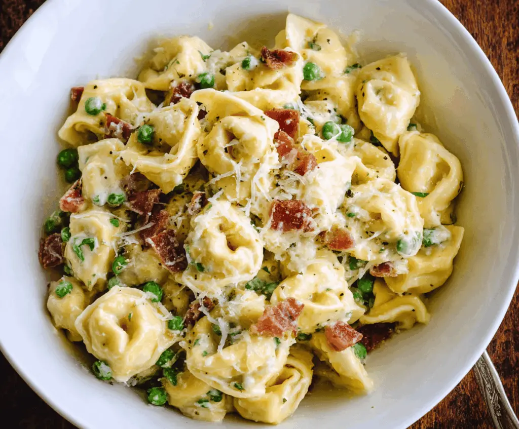 Creamy Tortellini Carbonara served in a white bowl with crispy pancetta and fresh herbs, ready to enjoy