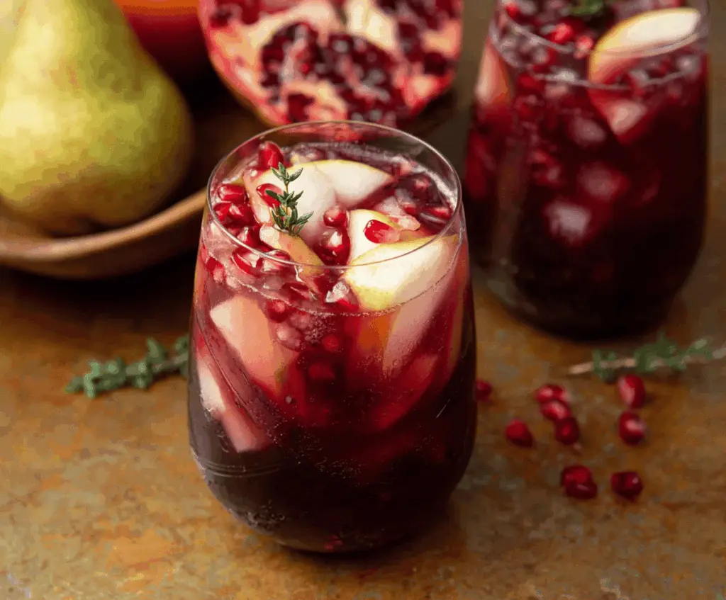 Refreshing Harvest Sangria with Pomegranate and Pears in a glass pitcher, garnished with fresh fruit slices, perfect for fall gatherings.