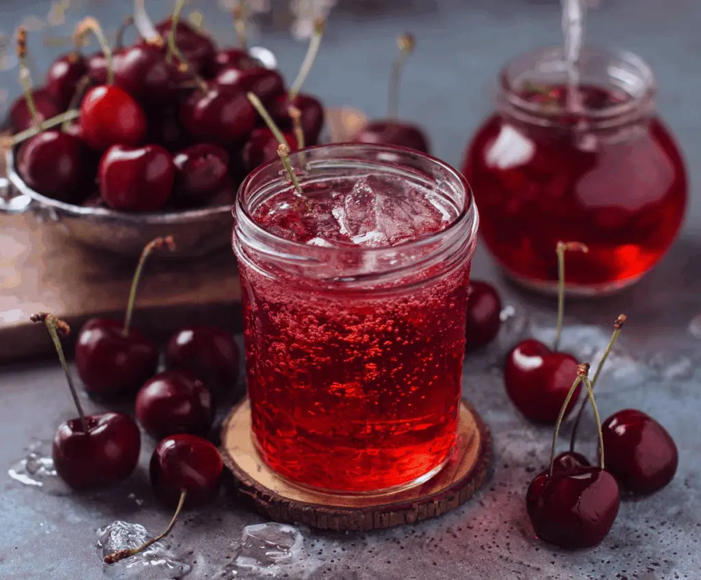 Refreshing Cherry Iced Tea in a clear glass garnished with fresh cherries and mint leaves on a summer table.
