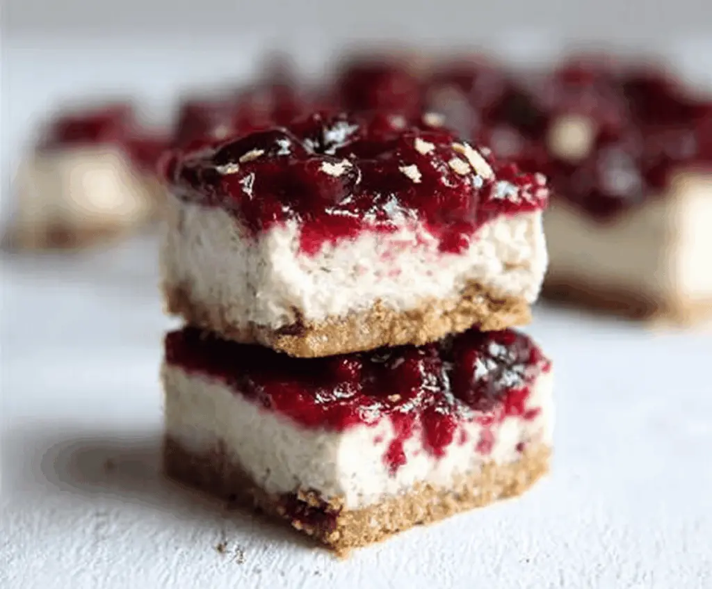 Vegan cranberry cheesecake bars with a creamy topping and fresh cranberries on top